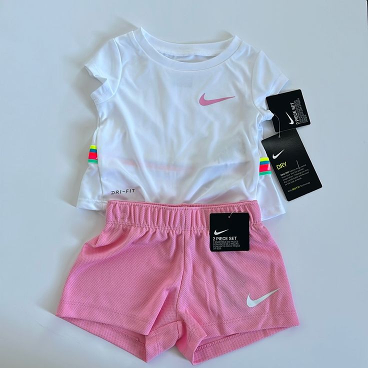 Nike Two Piece Summer Top And Shorts Set - Pink And White. Size 12 Months. 100% Polyester. Dri Fit Material. White Top With Pink Swoosh On The Front And Rainbow Band With Nike Logo Across The Back; Pink Elastic Waist Shorts With White Swoosh. This Is Absolutely Adorable!!! Spring Playwear Short Set, Spring Short Set For Playwear, White Cotton Short Set For Spring, Spring White Cotton Short Set, Nike Shorts For Summer Playwear, Nike Summer Shorts For Playwear, Sporty Spring Bottoms For Playtime, Sporty Spring Playtime Bottoms, Playful White Fitted Shorts