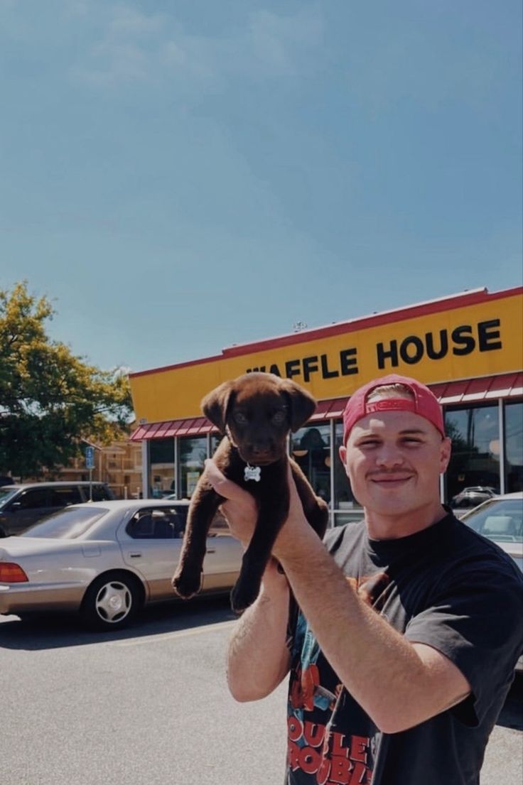 a man holding up a stuffed animal in front of a coffee house store with cars parked outside