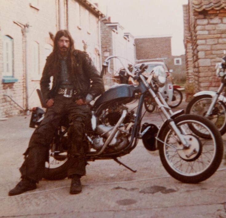 a man with long hair sitting on a motorcycle