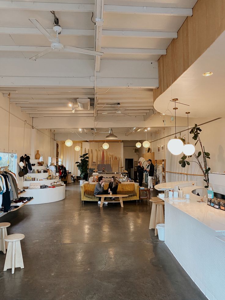 the inside of a clothing store with people shopping and sitting on couches in it