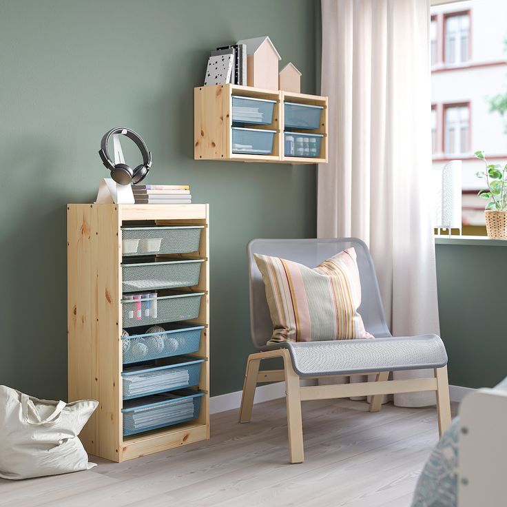 a living room with green walls and wooden shelves on the wall next to a chair