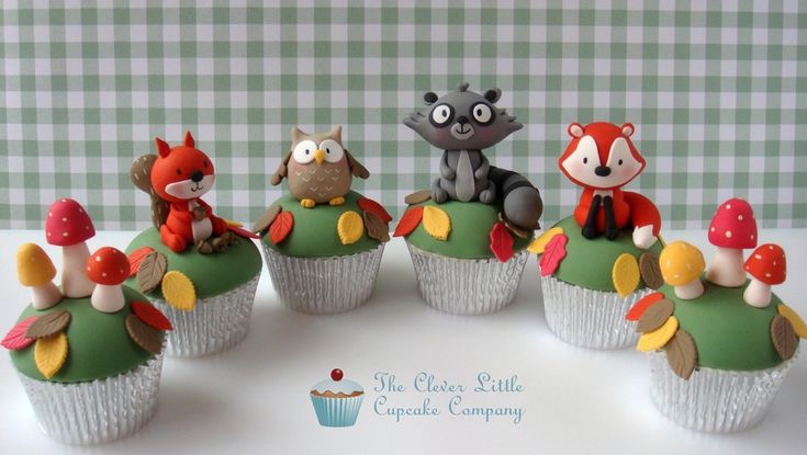 a group of cupcakes that have animals on top of them and mushrooms in the middle