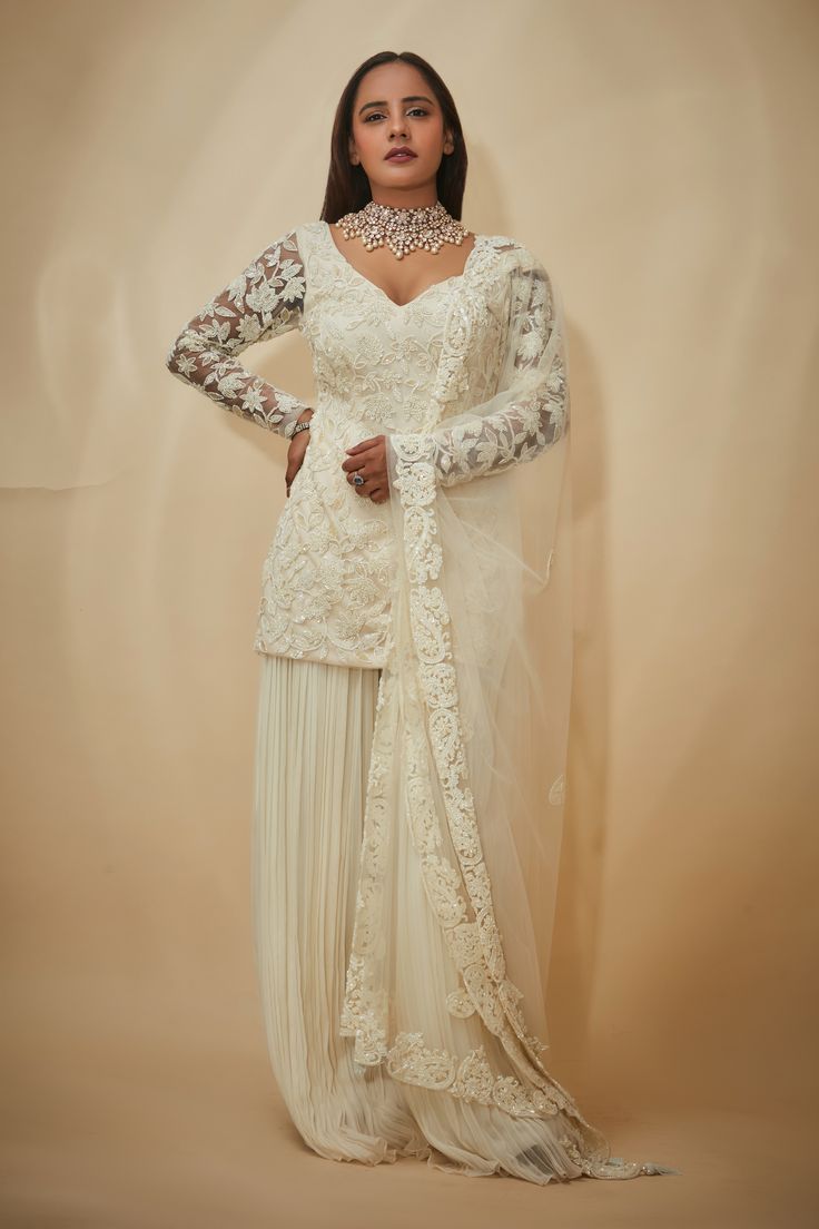 White kurta with floral hand embroidery. Comes with sharara and a dupatta.
Components: 3
Pattern: Hand embroidered
Type Of Work: Floral
Neckline: V Neck
Sleeve Type: Sheer Sleeves
Fabric: Tulle, Organza, Silk
Color: White
Other Details: 
Embroidered borders on dupatta
Occasion: Mehendi and Haldi,Sangeet - Aza Fashions Anarkali Sets With Chikankari Embroidery For Reception, Semi-stitched Chikankari Embroidery Sets For Reception, Wedding Palazzo Set With Sheer Dupatta And Long Sleeves, Long Sleeve Palazzo Set With Sheer Dupatta For Wedding, Designer Wear Floor-length Chikankari Sharara, Wedding Anarkali Palazzo Set With Resham Embroidery, Resham Embroidery Sharara For Reception, Floor-length Sharara With Chikankari Embroidery For Wedding, Bollywood Style Sharara With Chikankari Embroidery For Reception