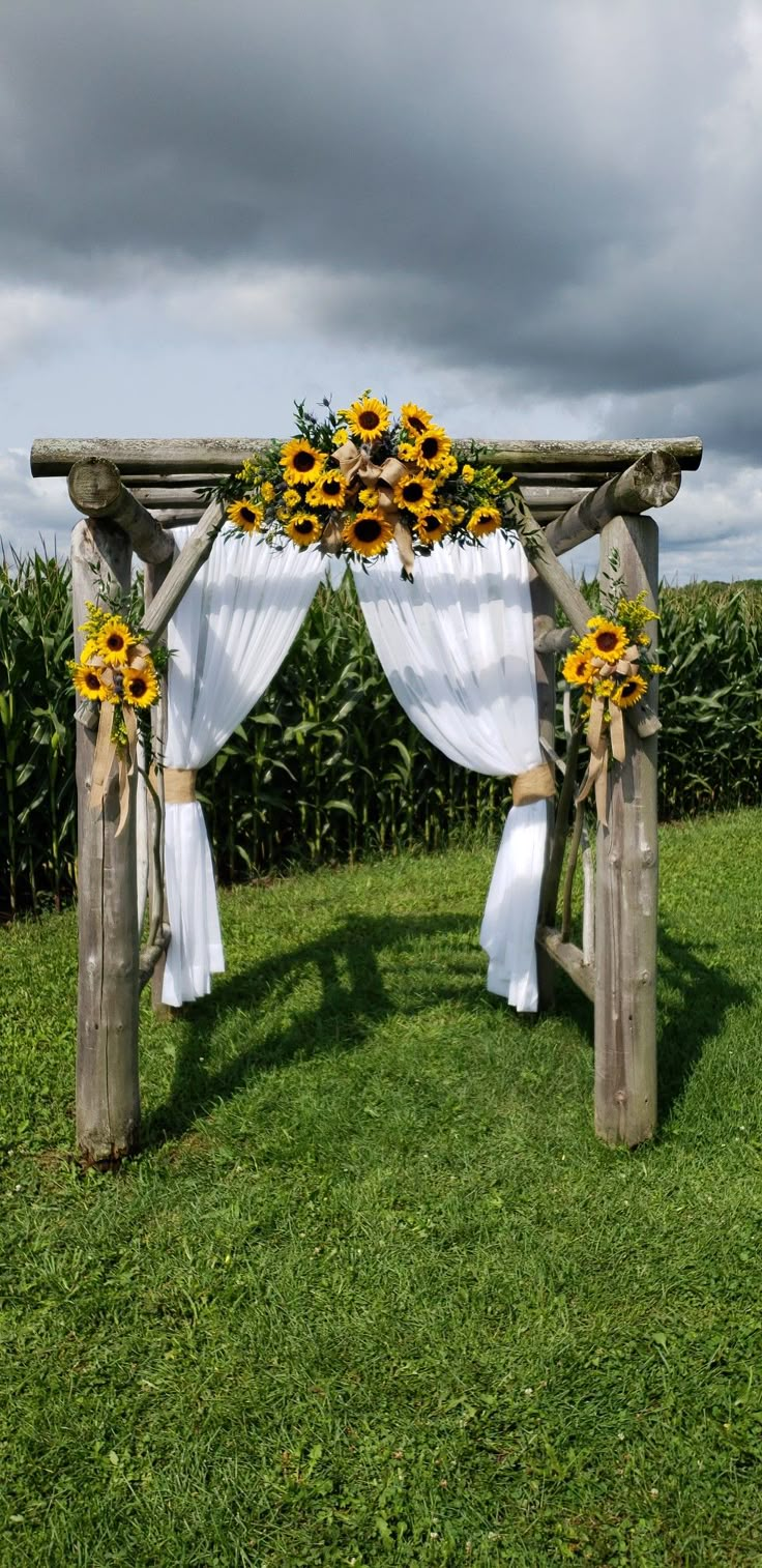 an outdoor wedding setup with sunflowers and white draping on the grass