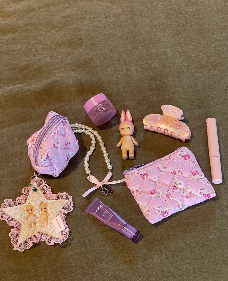 the contents of a doll's purse and accessories laid out on top of a bed