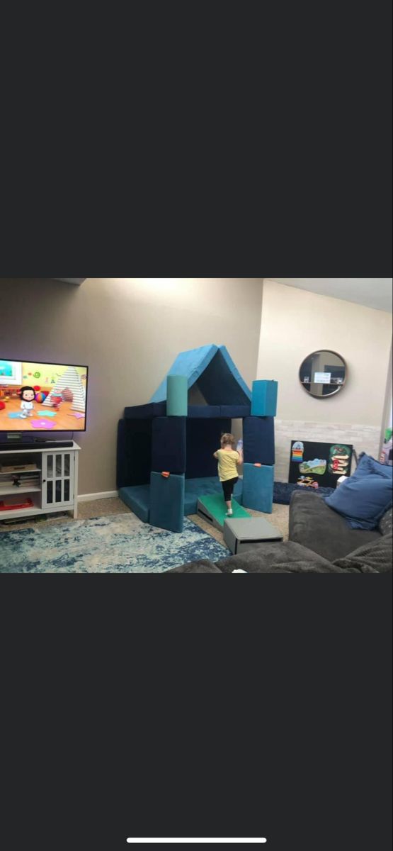 there is a child playing on the tv in this living room with blue and green furniture