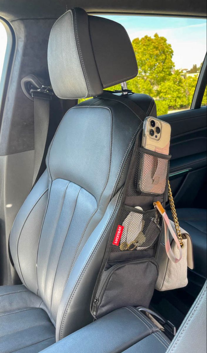 the back seat of a car with a cell phone and wallet hanging from it's holder