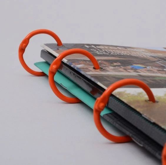 an open book with two orange rings on top of it and a magazine in the middle