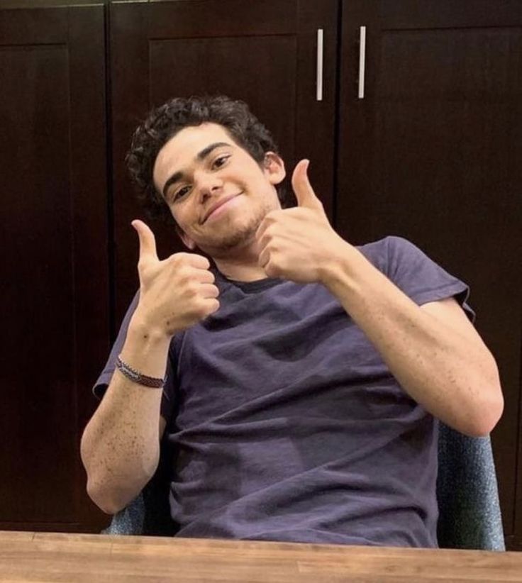 a man sitting at a table giving the thumbs up sign with his hand in front of him