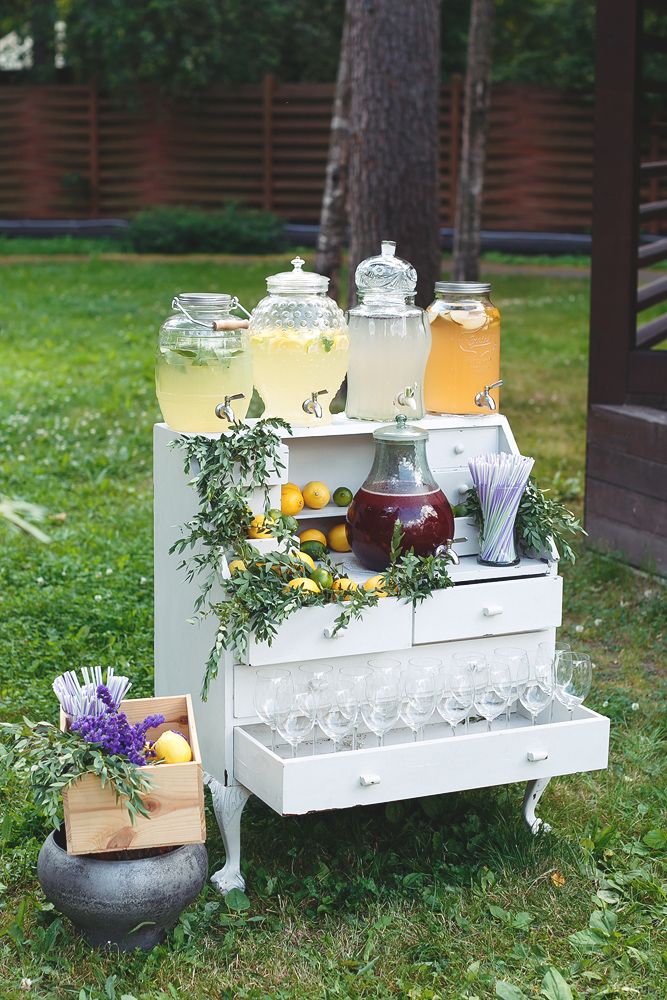 an old fashioned refrigerator is filled with drinks and flowers on the grass in front of a tree