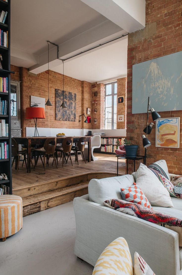 a living room filled with furniture next to a brick wall