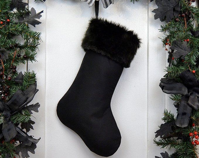 a christmas stocking hanging from a door with black ribbon and decorations around it,