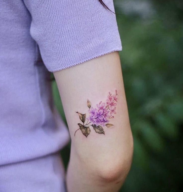 a woman's arm with a flower tattoo on the left side of her arm