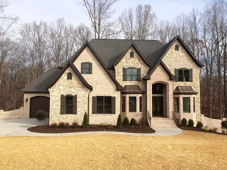 a large brick house in the middle of a wooded area with lots of trees and shrubs