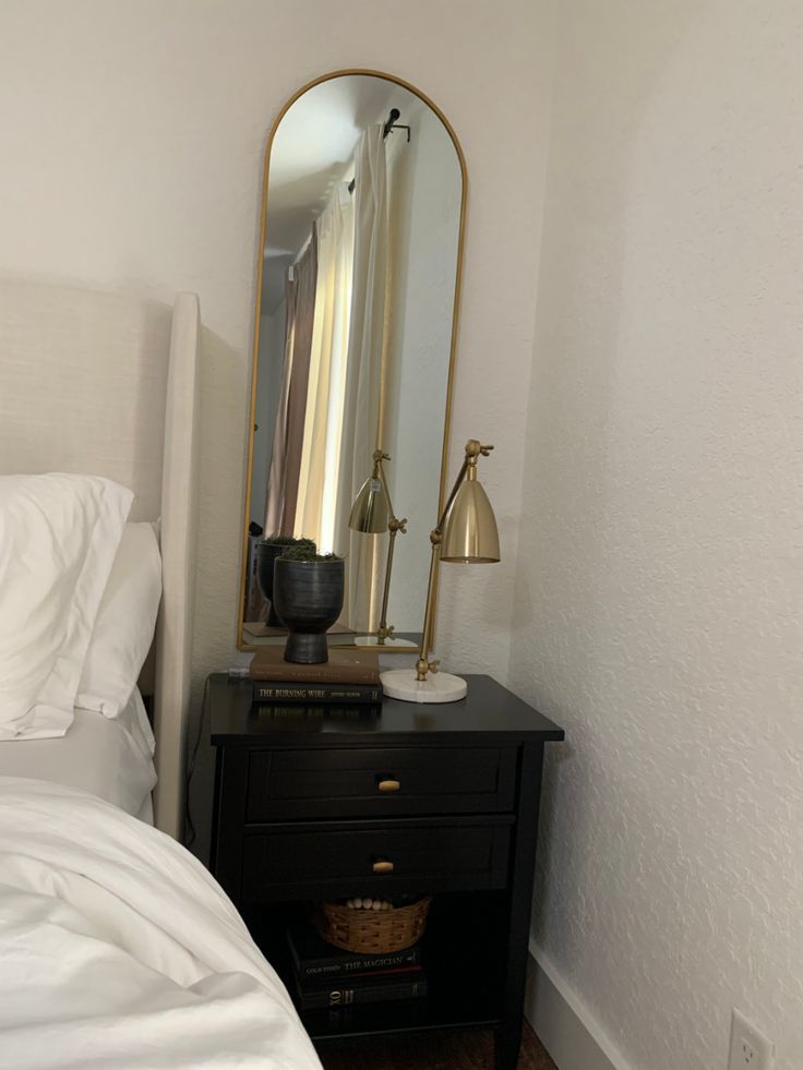 a bedroom with a bed, mirror and lamp on the side table in front of it