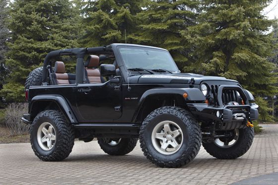 a black jeep is parked in front of some trees