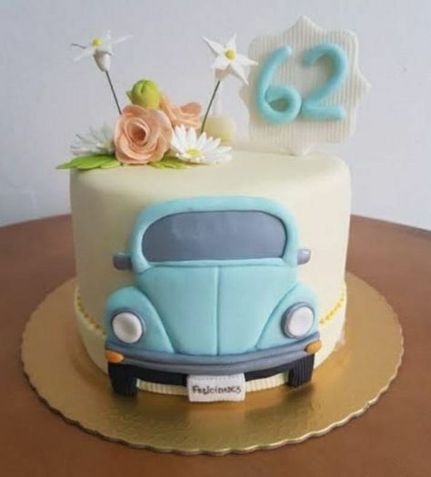 a cake decorated with an old blue car and flowers on top of a wooden table