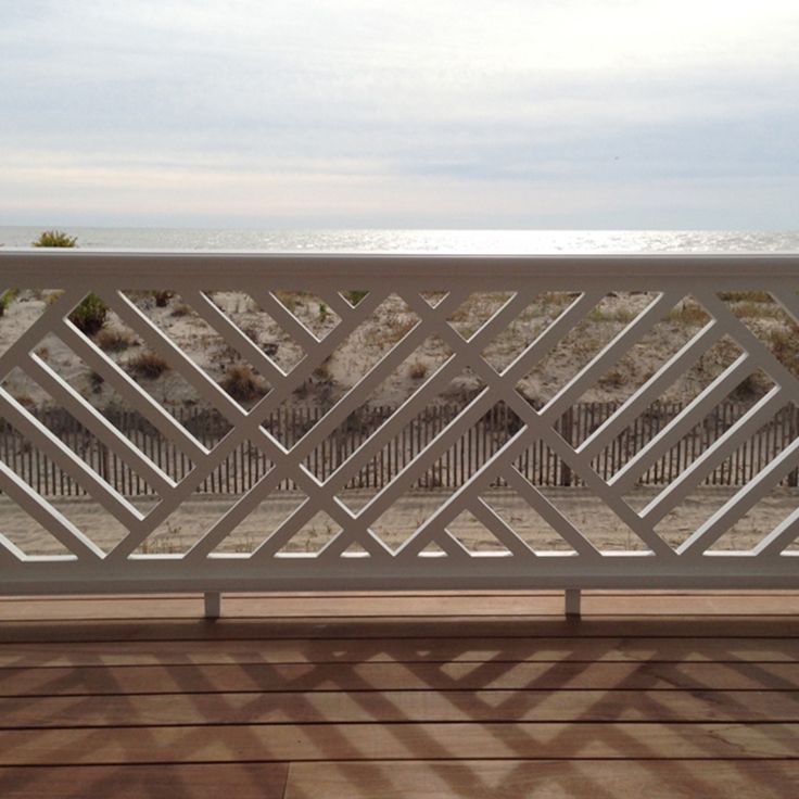 a white balcony overlooking the beach and ocean with an iron gate on it's side