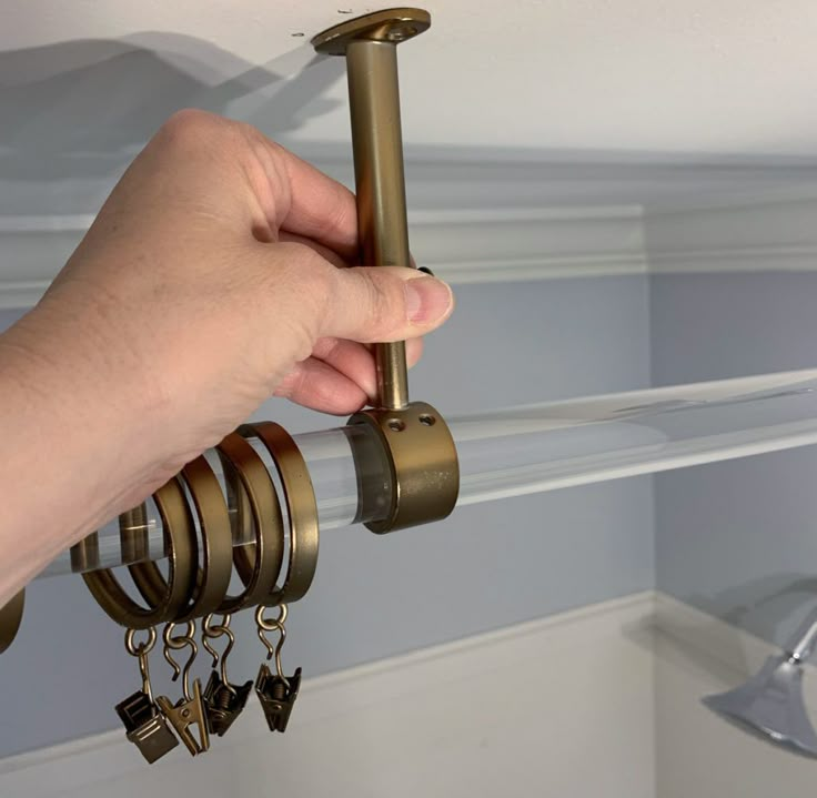 a hand is holding keys in front of a shelf with several key rings hanging from it