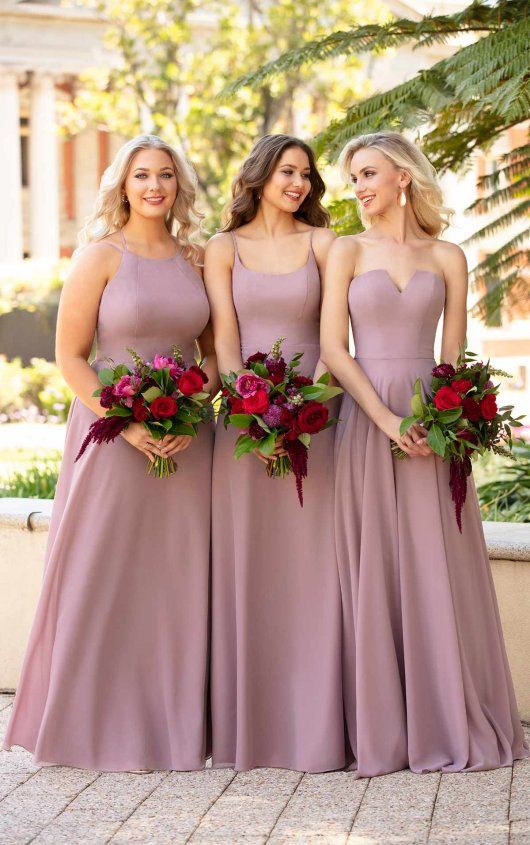 the bridesmaids are all dressed in dusty pink dresses with red flowers on their bouquets