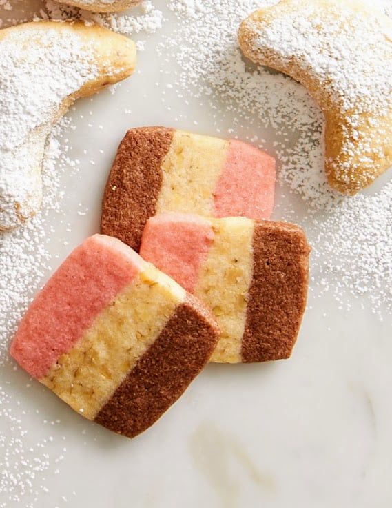 three different colored pastries sitting on top of a white table covered in powdered sugar