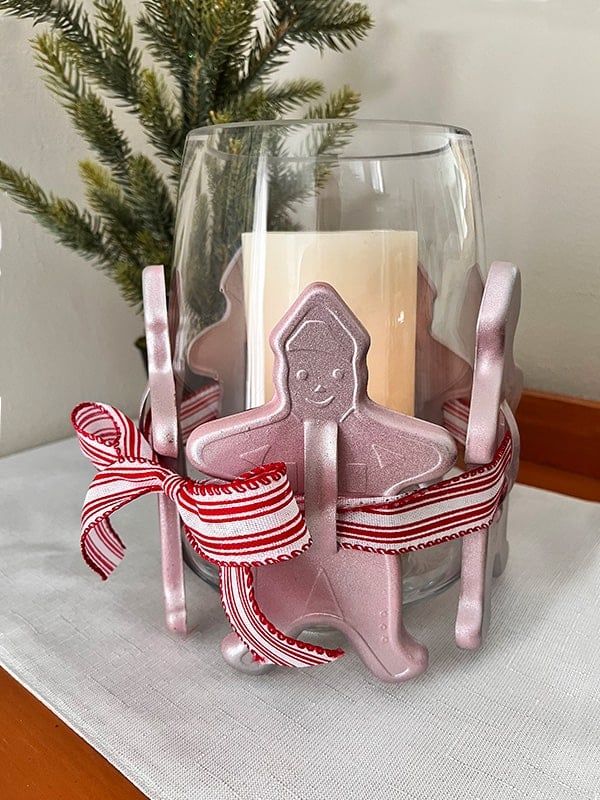 a glass vase filled with candles on top of a white cloth covered table next to a christmas tree