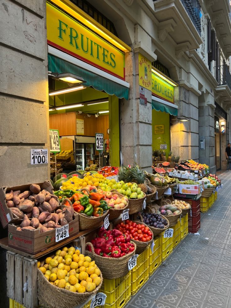 an outdoor market with fruits and vegetables on display in front of the store's windows