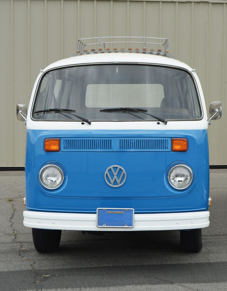 a blue and white vw bus parked in front of a building