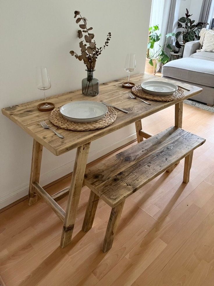 a wooden table with two plates on it and a bench in front of the table