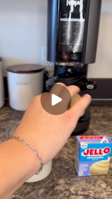 someone is holding their hand out in front of the coffee maker and carton of jello