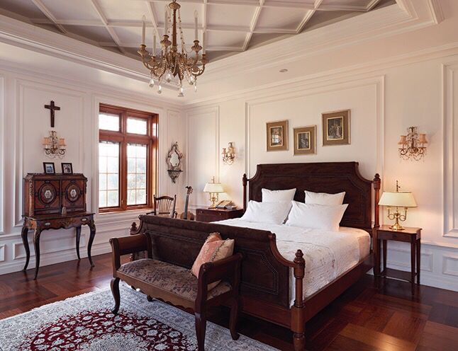 a large bedroom with white walls and wood flooring has a chandelier hanging from the ceiling