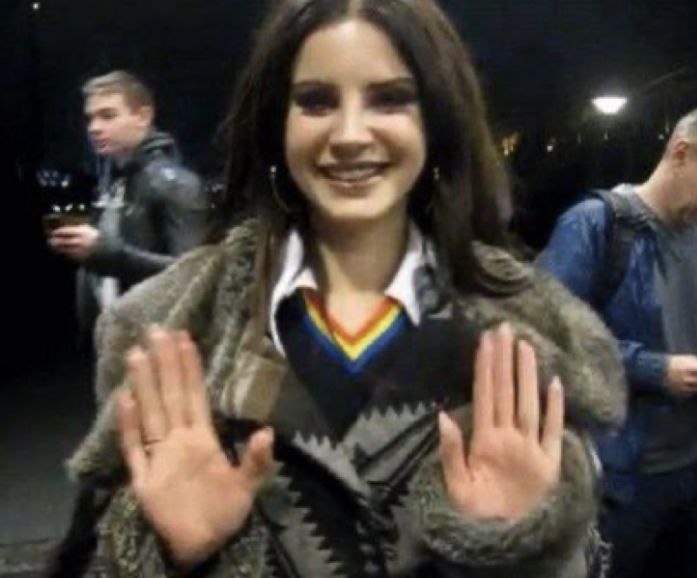 a woman is smiling and holding her hands up