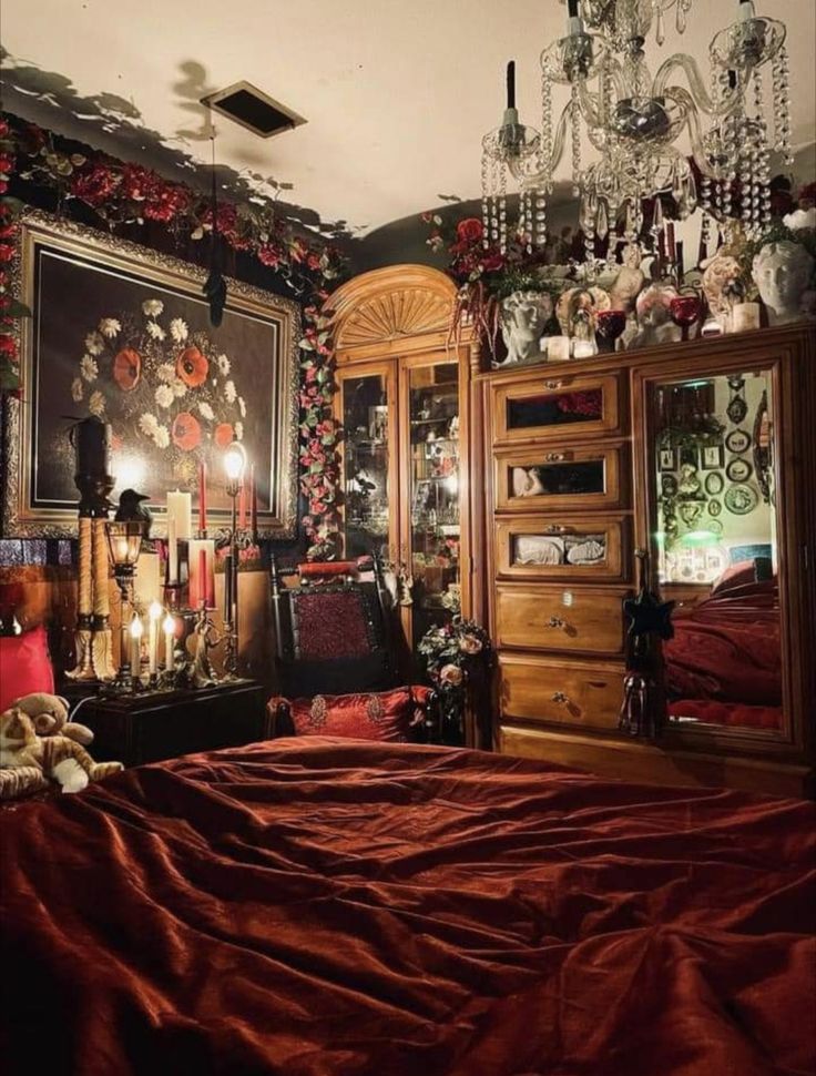 a bedroom with red sheets and chandelier hanging from the ceiling, decorated with flowers