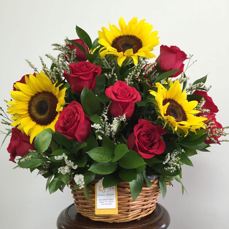 a basket filled with red roses and yellow sunflowers