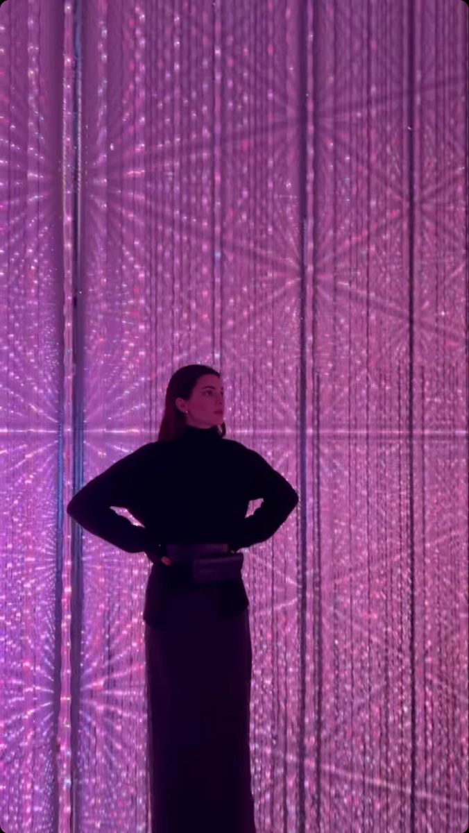 a woman standing in front of a purple curtain