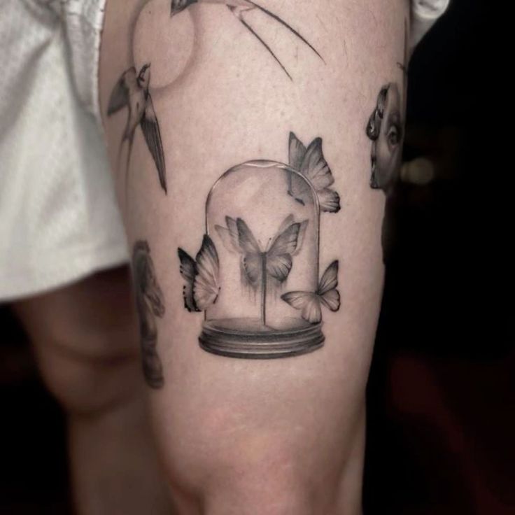 a person with a tattoo on their leg that has birds flying around it and a glass dome in the middle