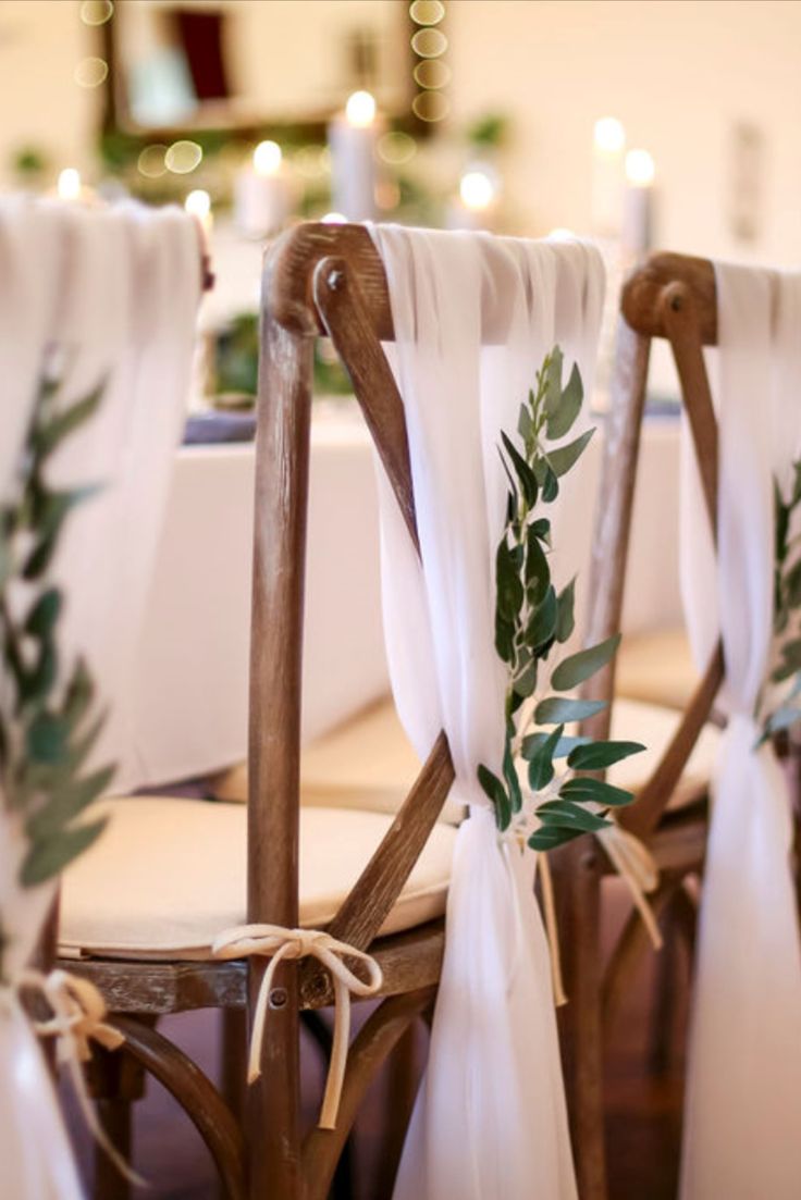 the chairs are decorated with greenery and ribbons