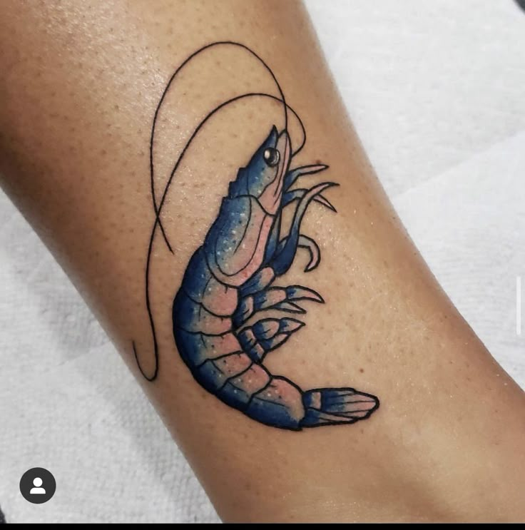 a tattoo on the leg of a woman with a blue lobster in it's claws