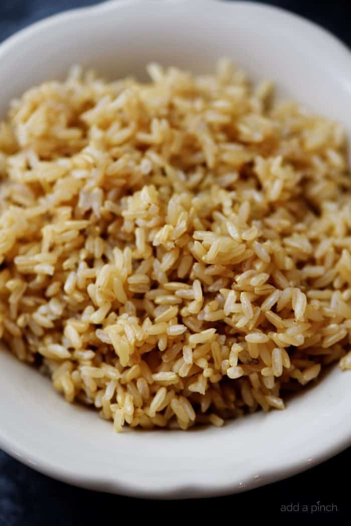 a white bowl filled with brown rice on top of a black tablecloth covered table