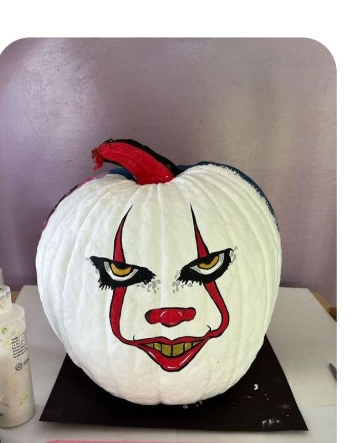 a white pumpkin with a clown face painted on it