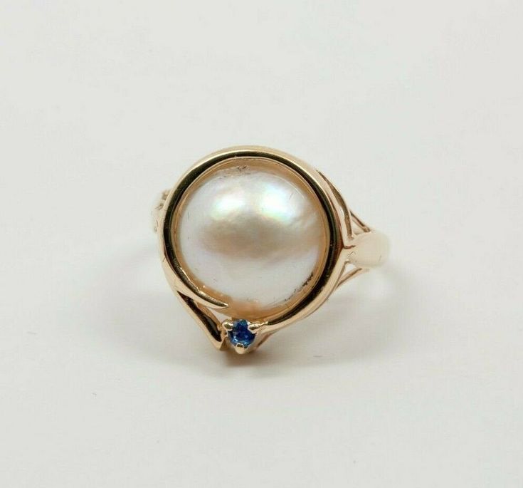 14K yellow gold Mabe pearl and sapphire accent ring, 12 mm 1/2 pearl with bright blue sapphire accent to top circa 1990, ring size 6, weight 3.6 grams Stock # BRT2027 Most rings are sizable for a small fee. If the ring you are considering is the incorrect size contact us for a quote. This listing contains photographs of the actual item you will receive. Our items are in excellent condition with little or no signs of wear and many are one of a kind pre-owned estate finds. Please look closely at t 14k Stamped Fine Jewelry Pearl Ring, 14k Stamped Fine Pearl Ring, Anniversary Cabochon Pearl Ring, Fine Jewelry Pearl Cabochon Ring For Anniversary, Heirloom Pearl Ring With Birthstone, Heirloom Pearl Birthstone Ring, Unique Pearl Ring For Anniversary, Mabe Pearl, Boston Ma