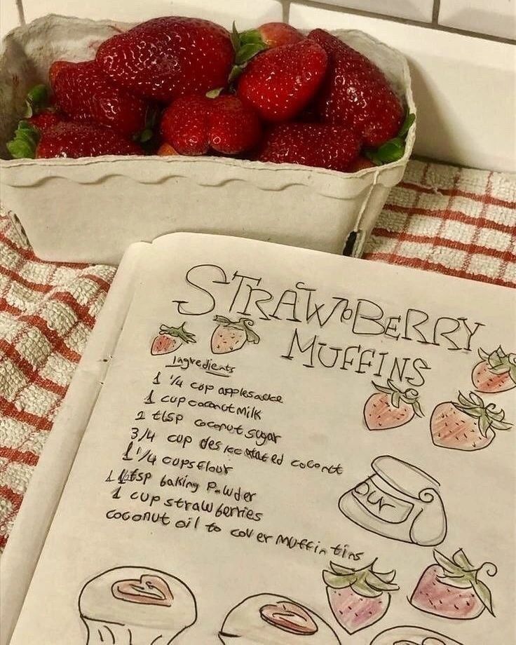 strawberries are sitting in a bowl next to a recipe book