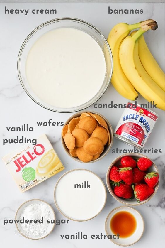 ingredients to make strawberry shortcakes laid out on a marble counter top, including milk, sugar, strawberries and bananas