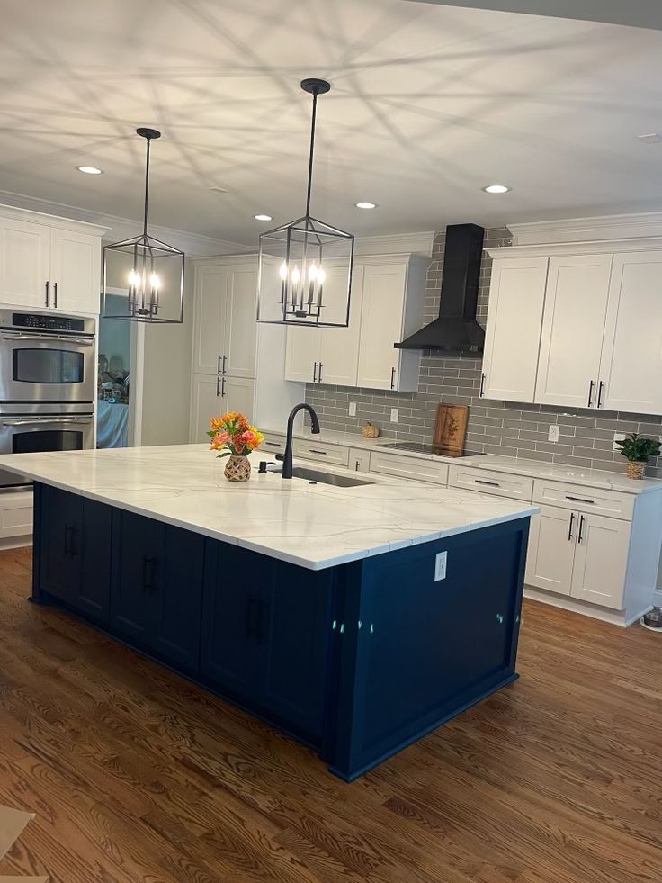 a kitchen with white cabinets and blue island