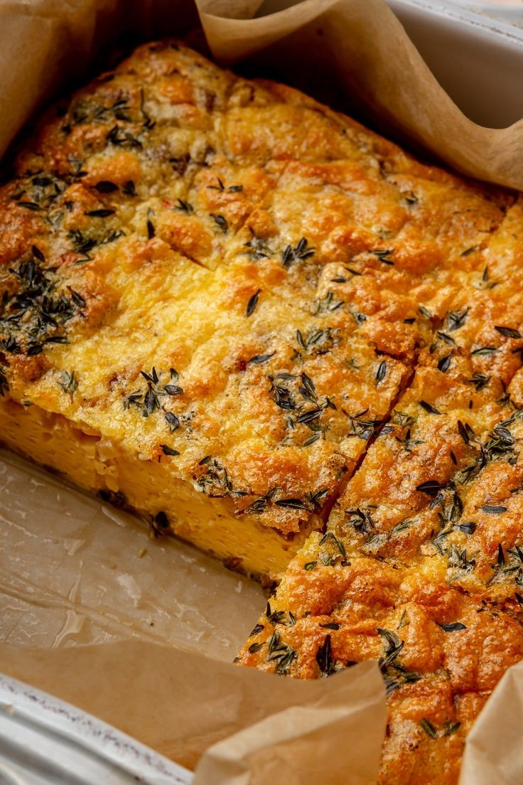 a casserole with cheese and herbs is in a paper container on the table