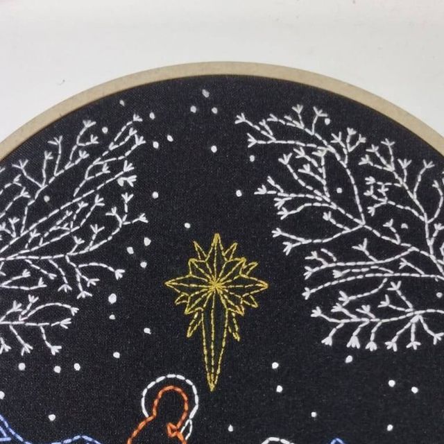 an embroidered christmas ornament with snowflakes and stars in the night sky