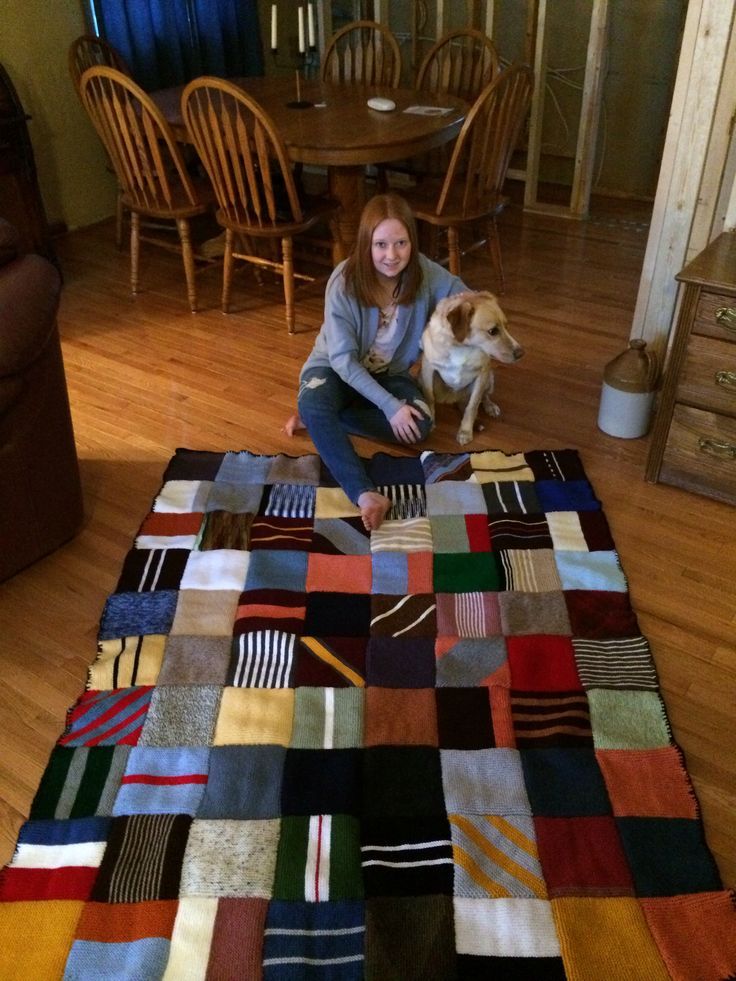 a woman sitting on the floor with her dog next to a multicolored quilt