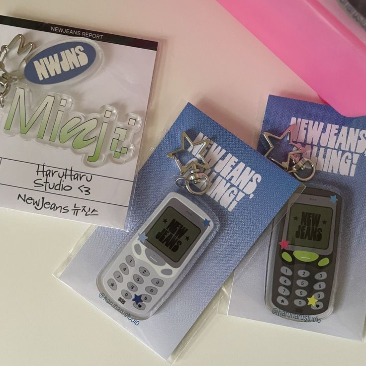 two cell phones sitting on top of each other in front of a book and keychain