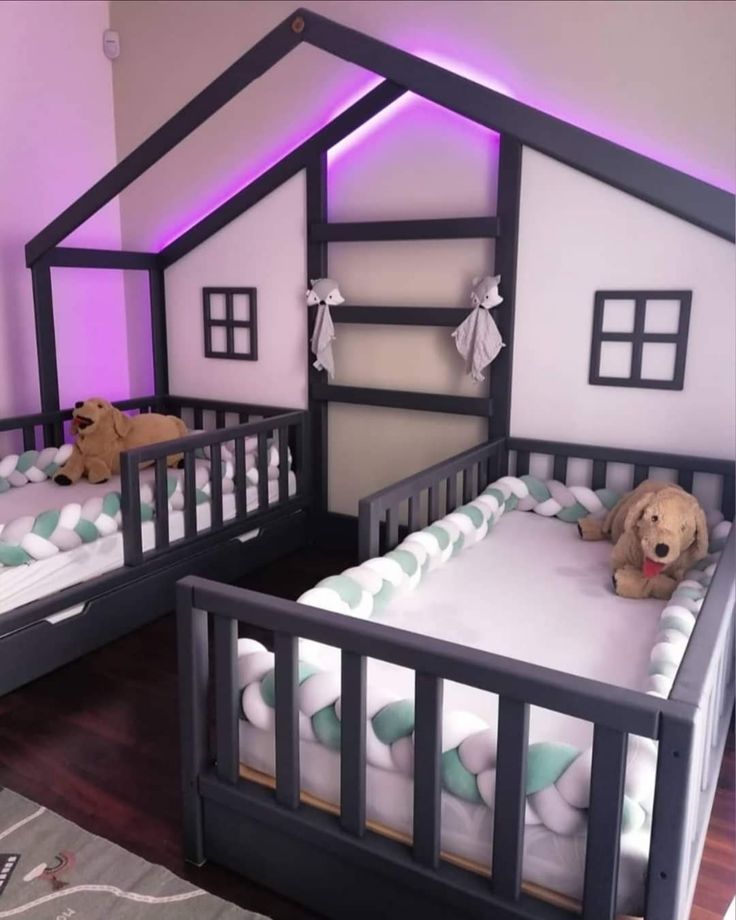 two beds with teddy bears on them in a room that has white walls and purple lighting