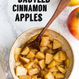 a bowl filled with sliced cinnamon apples on top of a table next to an apple